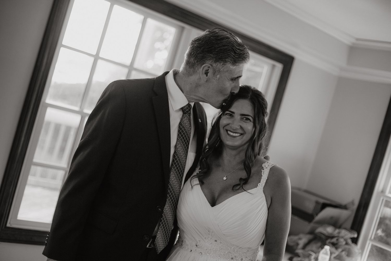 A wedding couple shares intimate moments while walking up a staircase in a bright indoor setting.
