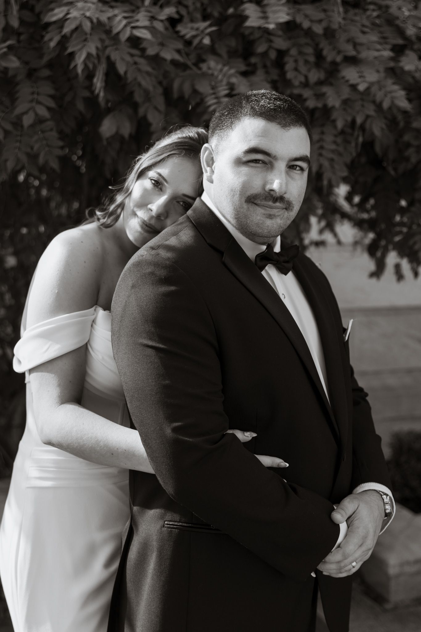 Black and white photo series captures intimate moments between newlyweds in formal attire.