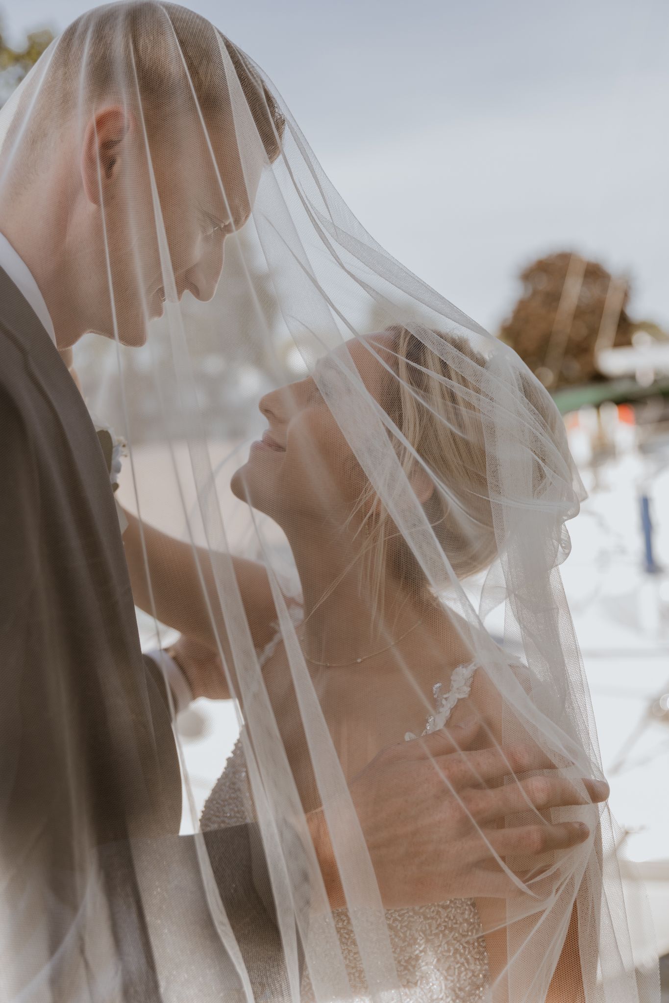 A romantic wedding moment captured through delicate veil during an intimate ceremony.
