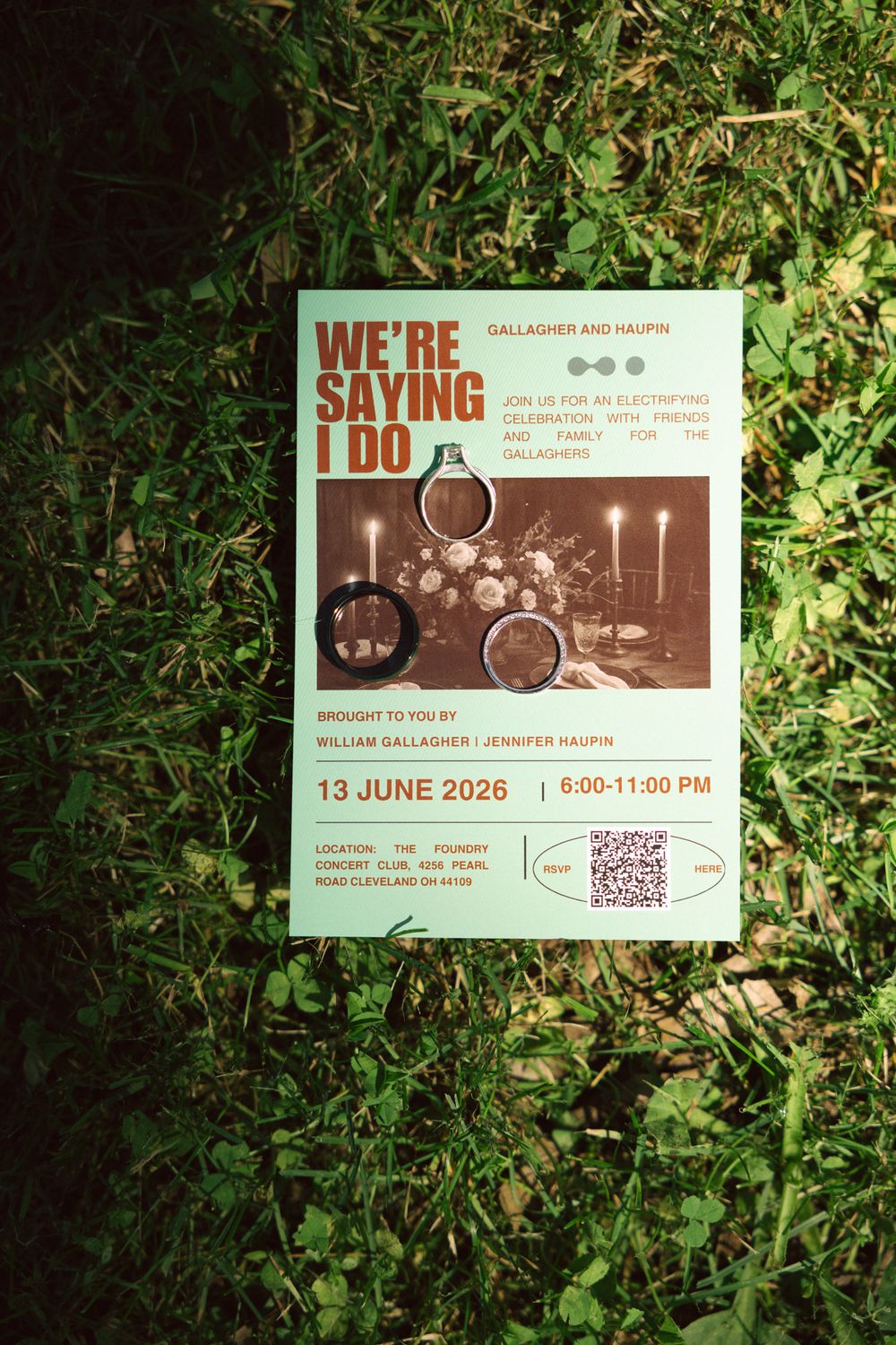 Wedding save-the-date card reading We're Saying I Do for Gallagher and Haupin on June 13 2026 laid on green grass.