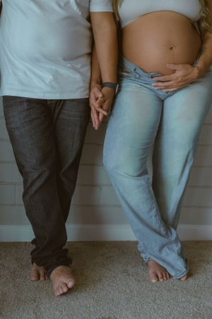 Intimate barefoot poses showing couple in white shirts and denim against white wall.
