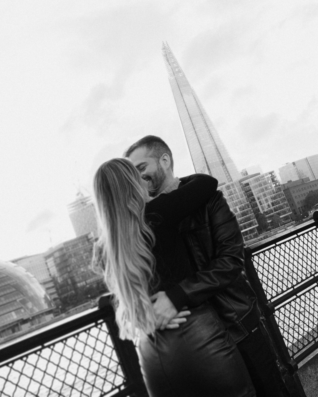 Couple sharing romantic moment with The Shard building in London backdrop.