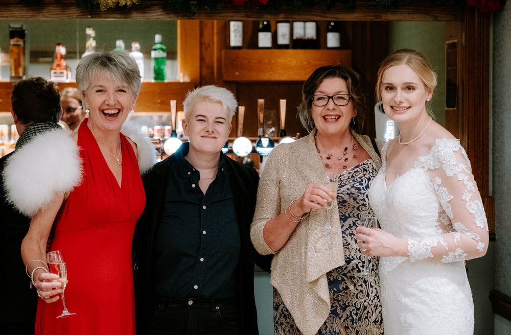 Wedding celebration with guests laughing and enjoying festivities in a rustic indoor venue.