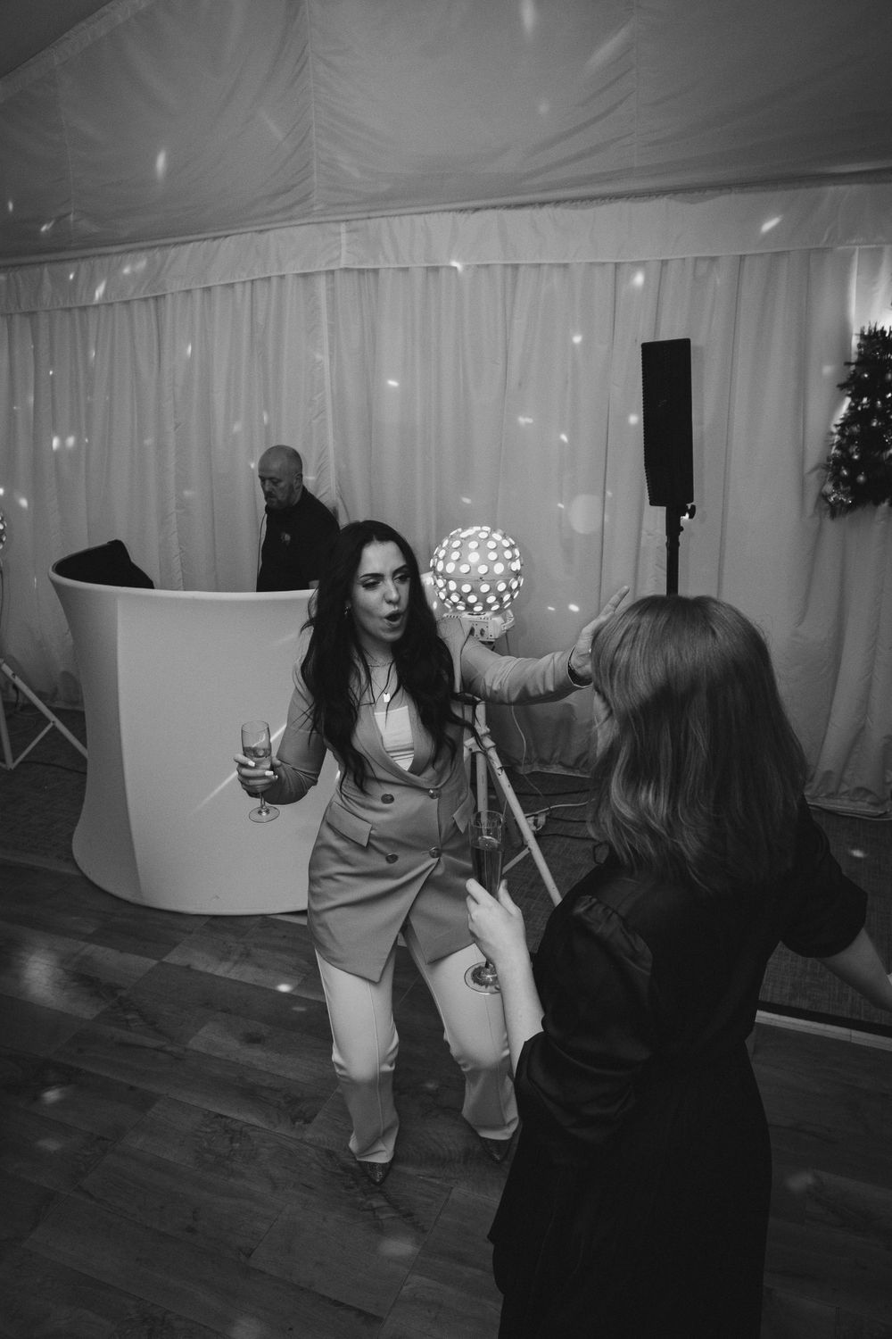 Guests perform fun dance moves on the dance floor at an indoor celebration with string lights.