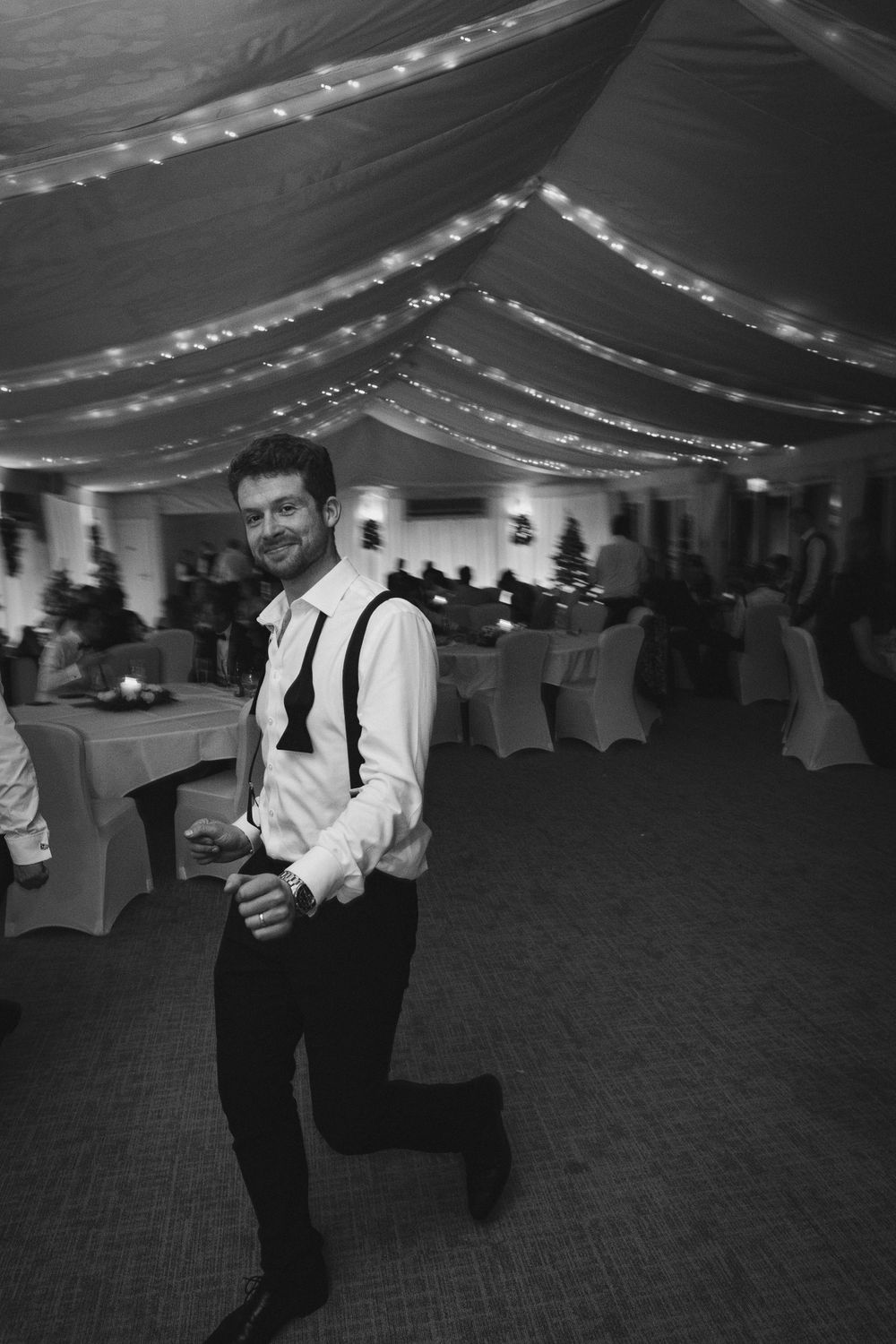 Black and white photos of guests dancing under string lights in a decorated reception venue.