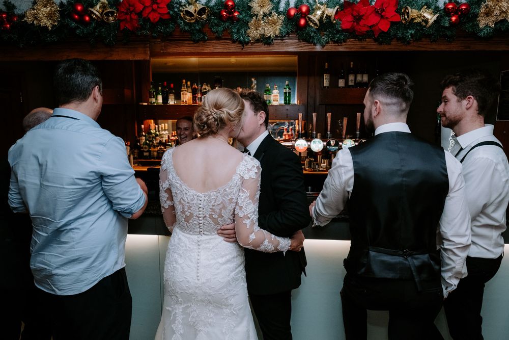 Reception venue with floral decorations and bar area where guests are mingling and celebrating.
