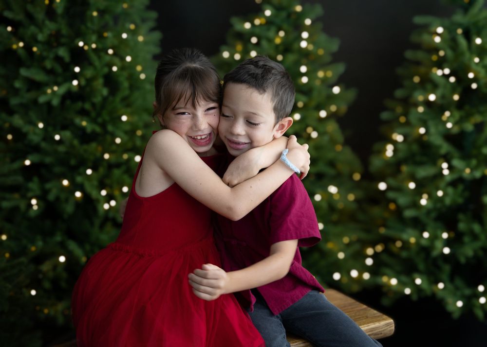 Best Hong Kong family photographer Christmas photo shoot portrait two siblings front of Christmas trees with bokeh lights