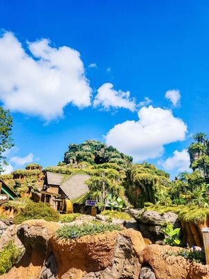 A beautiful landscape view of damaged tree roots and rocks against a vibrant blue sky with puffy white clouds.