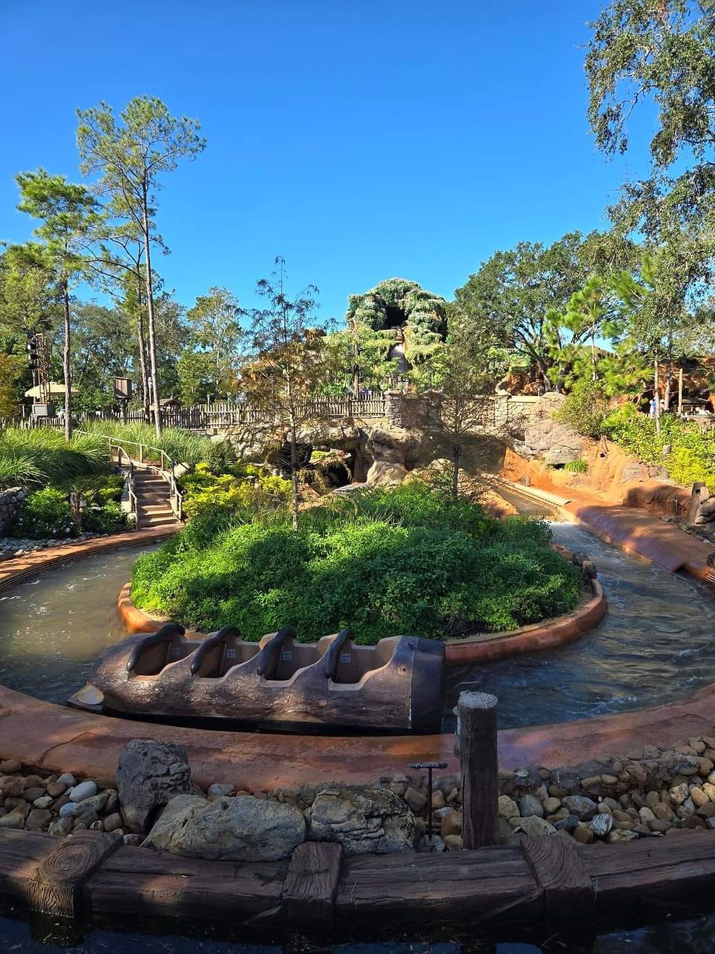 A panoramic view of a modern garden pathway with raised stone planters and native landscaping in a natural setting.