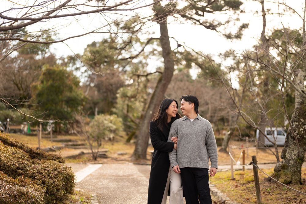 Couple gazing at each other lovingly while walking on a path in a peaceful Japanese garden.