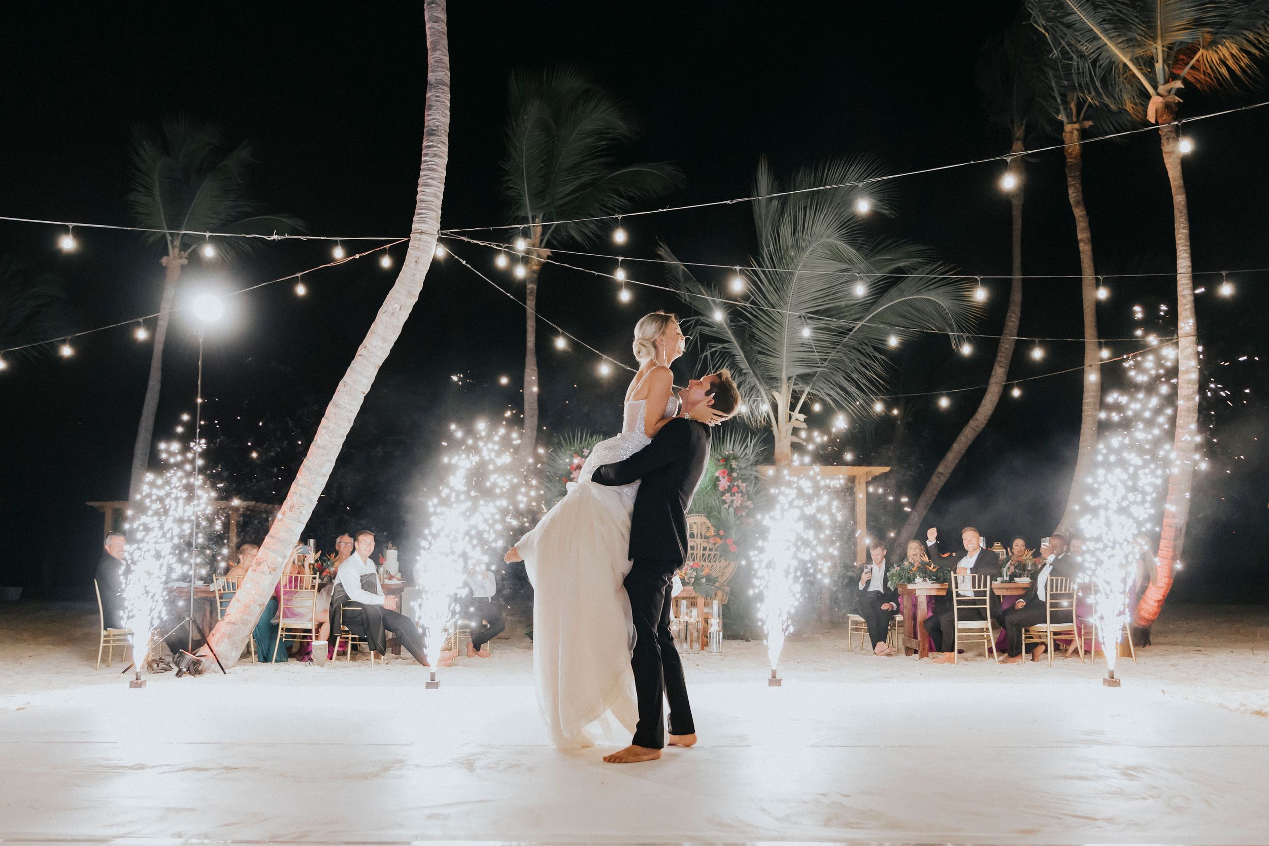 A romantic first dance at a beach wedding reception with sparklers creating a magical atmosphere.