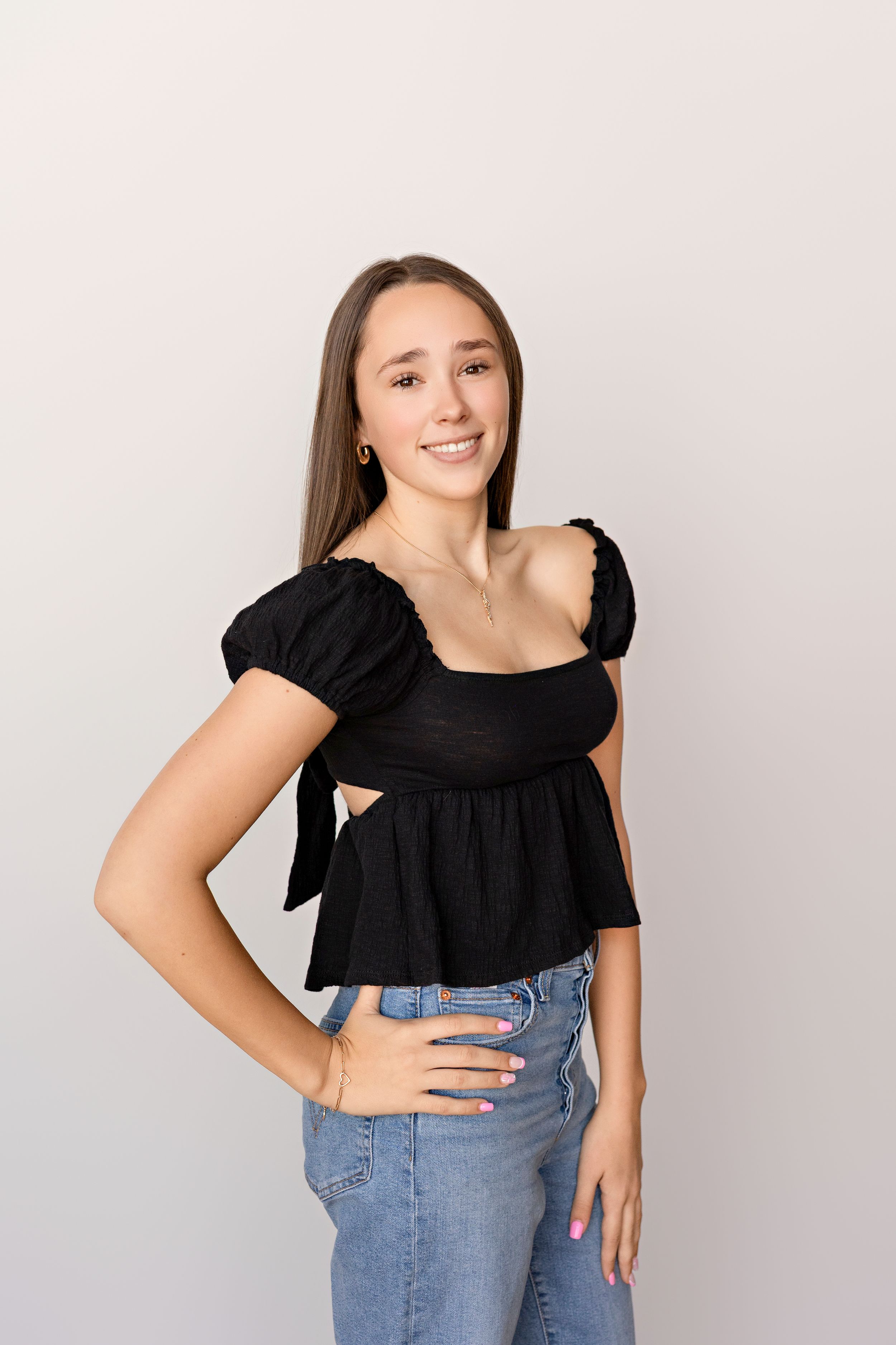 A person wearing a black puff-sleeve crop top and blue jeans poses against a light gray background.