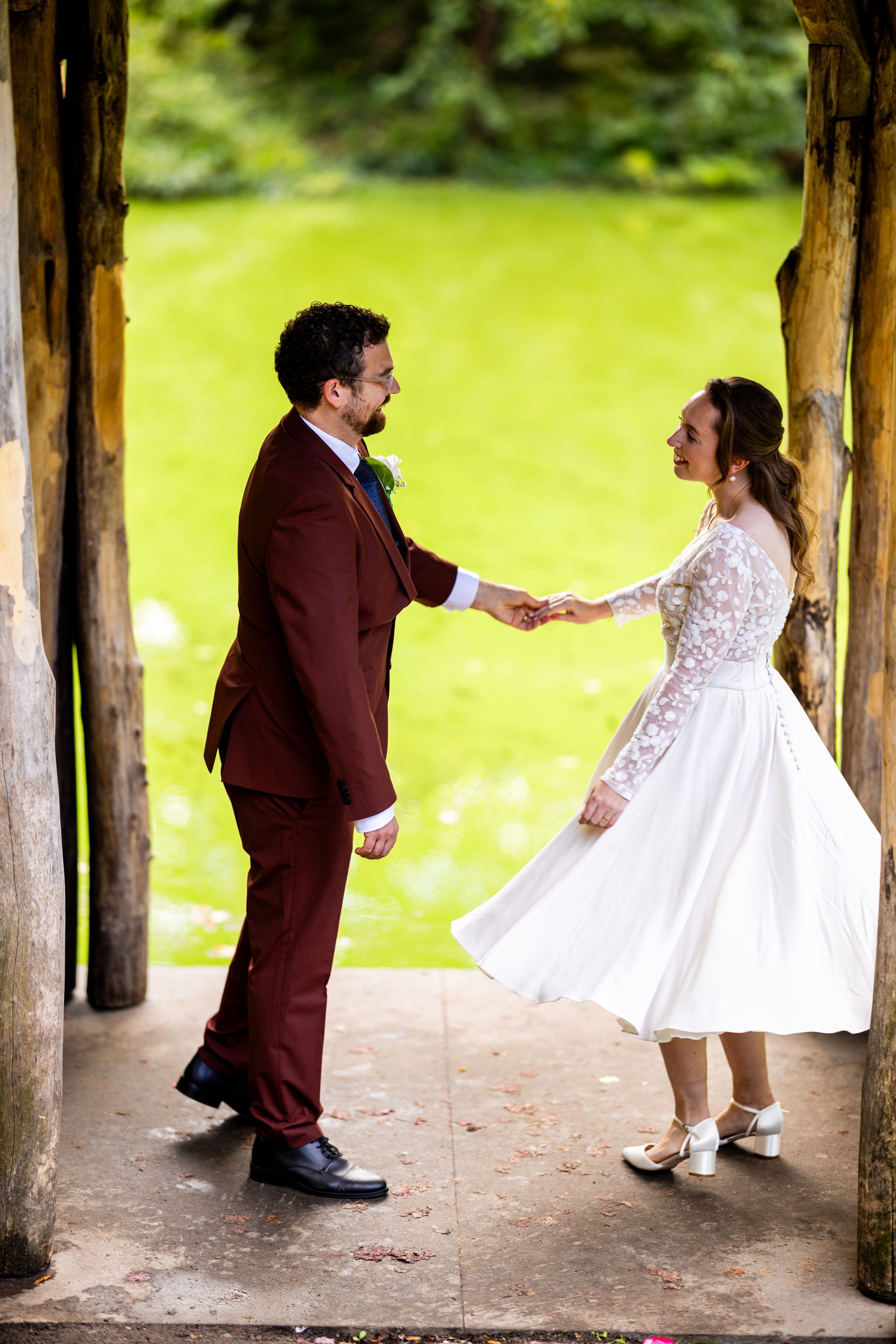 A playful wedding dance moment captured under a wooden pergola.