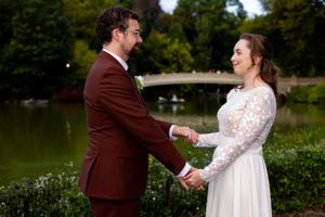 A wedding couple shares a joyful moment by a lake during their outdoor ceremony.