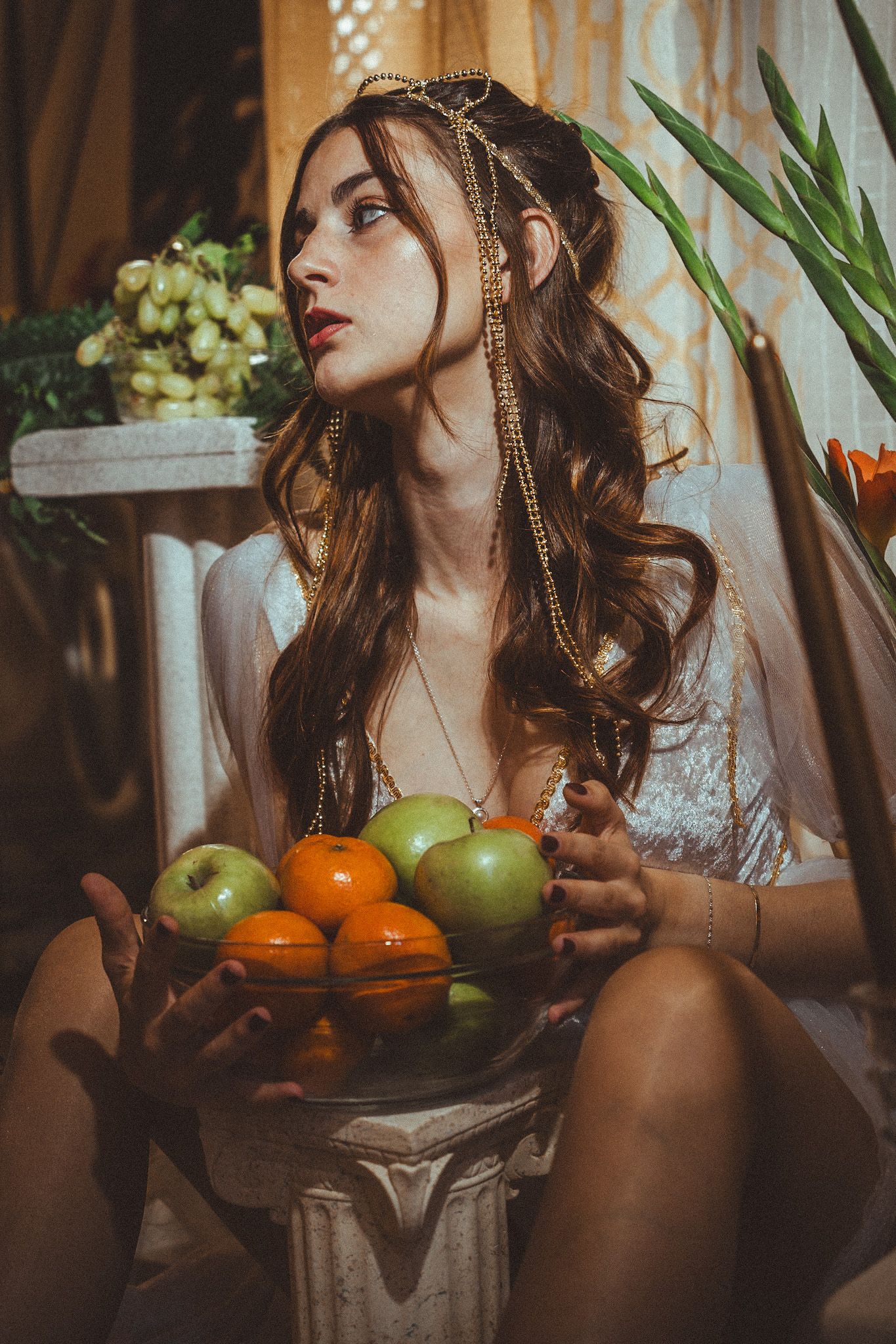 Ethereal portrait with bowl of citrus fruits in vintage-inspired setting with indoor plants.