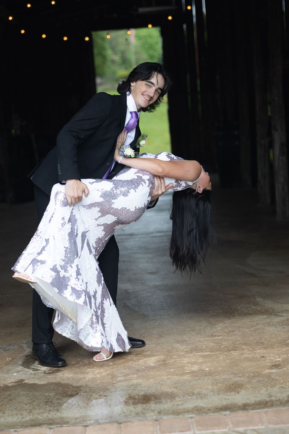 A romantic dance dip performed on a rustic floor with string lights visible in the background.