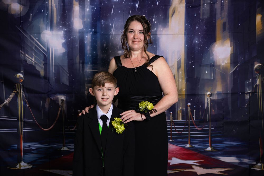 Formal portrait of two people against a cityscape backdrop with ropes and lights.