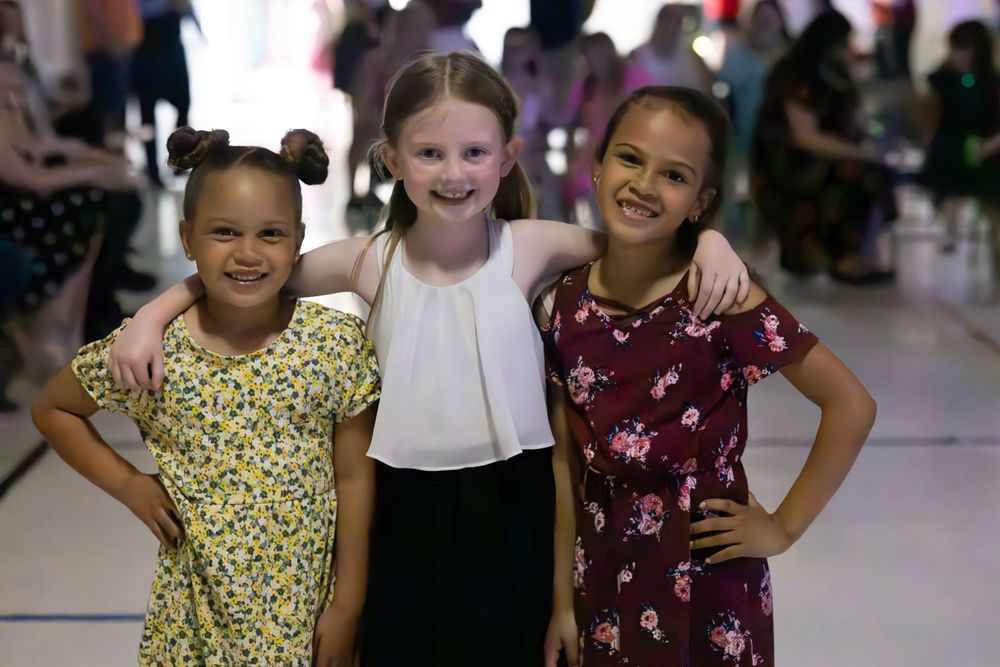 Three young friends pose together at what appears to be a school dance or social event.