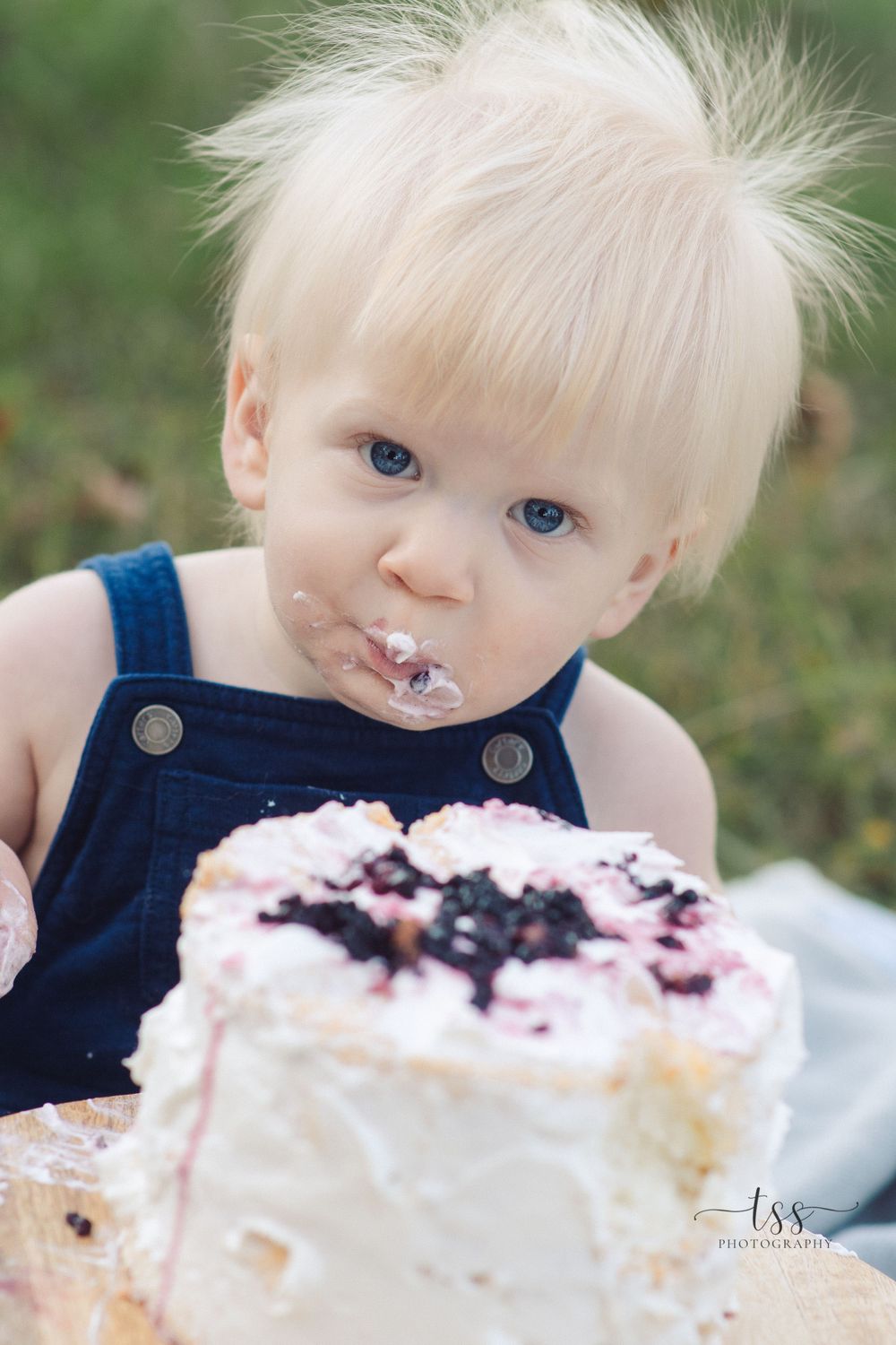 Close up of toddler with frosting-covered face during cake smash photo session.