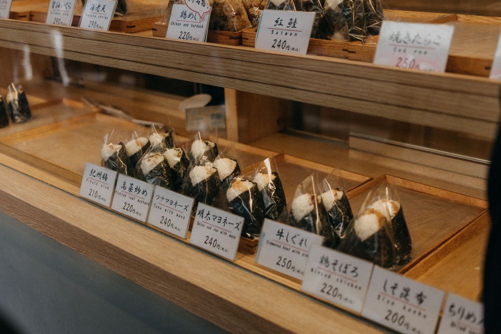 Display case of neatly arranged onigiri rice balls with price tags in a Japanese shop.