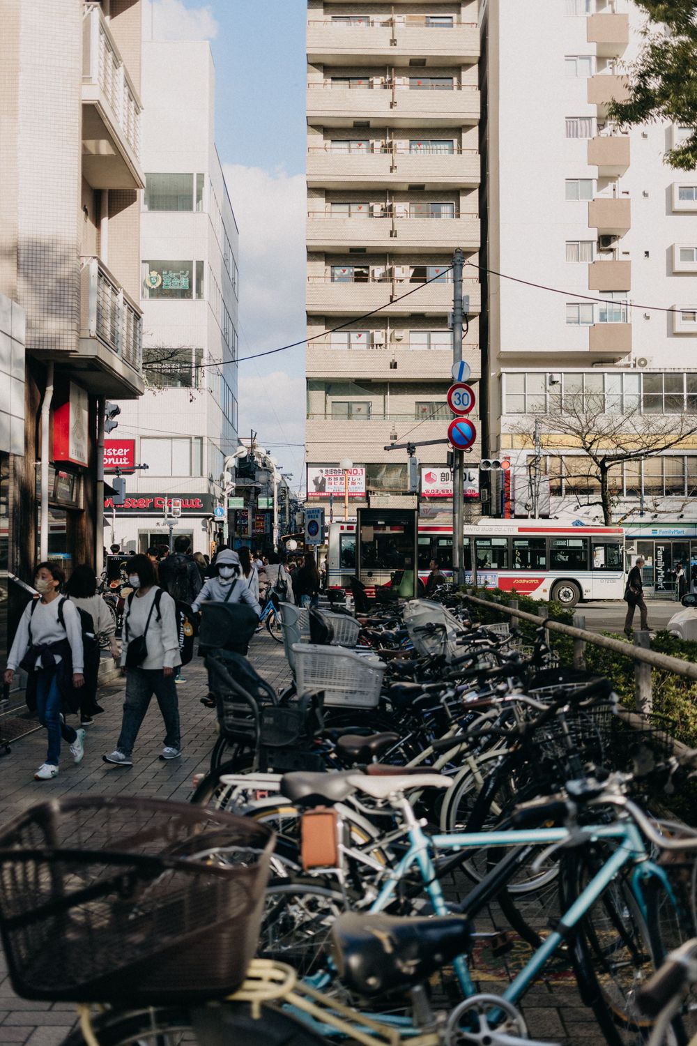 Urban street scene in Japan with parked bicycles and apartment buildings in the background.