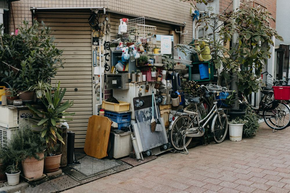 Cluttered storefront in Japan with potted plants and bicycles.