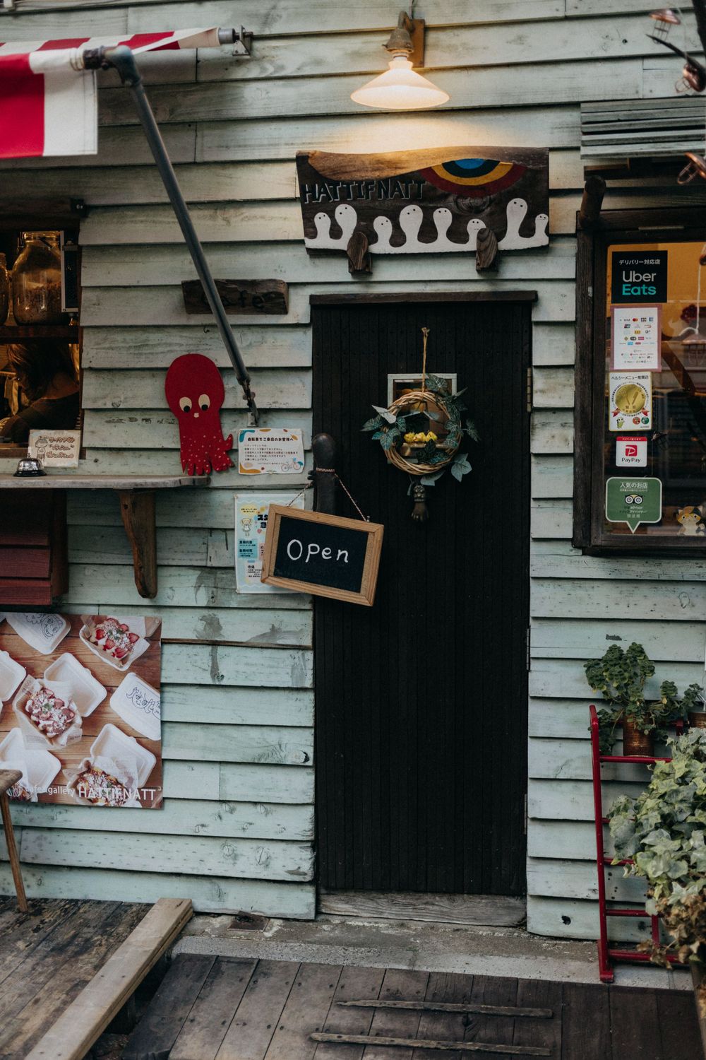 Rustic wooden storefront with a black door and hanging decorations.