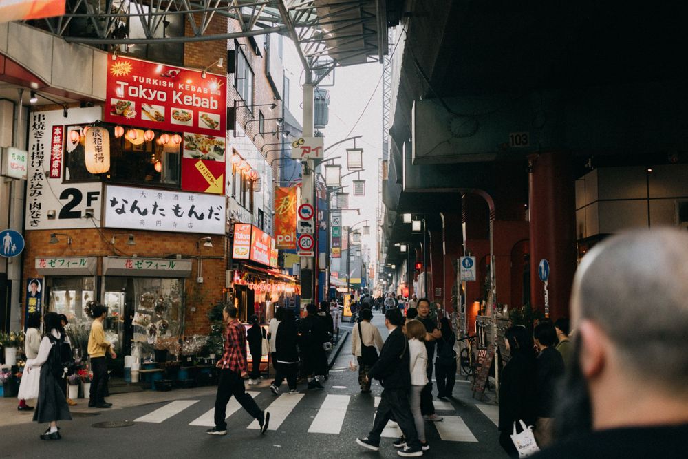 Busy Japanese street with neon signs and shops during daytime.