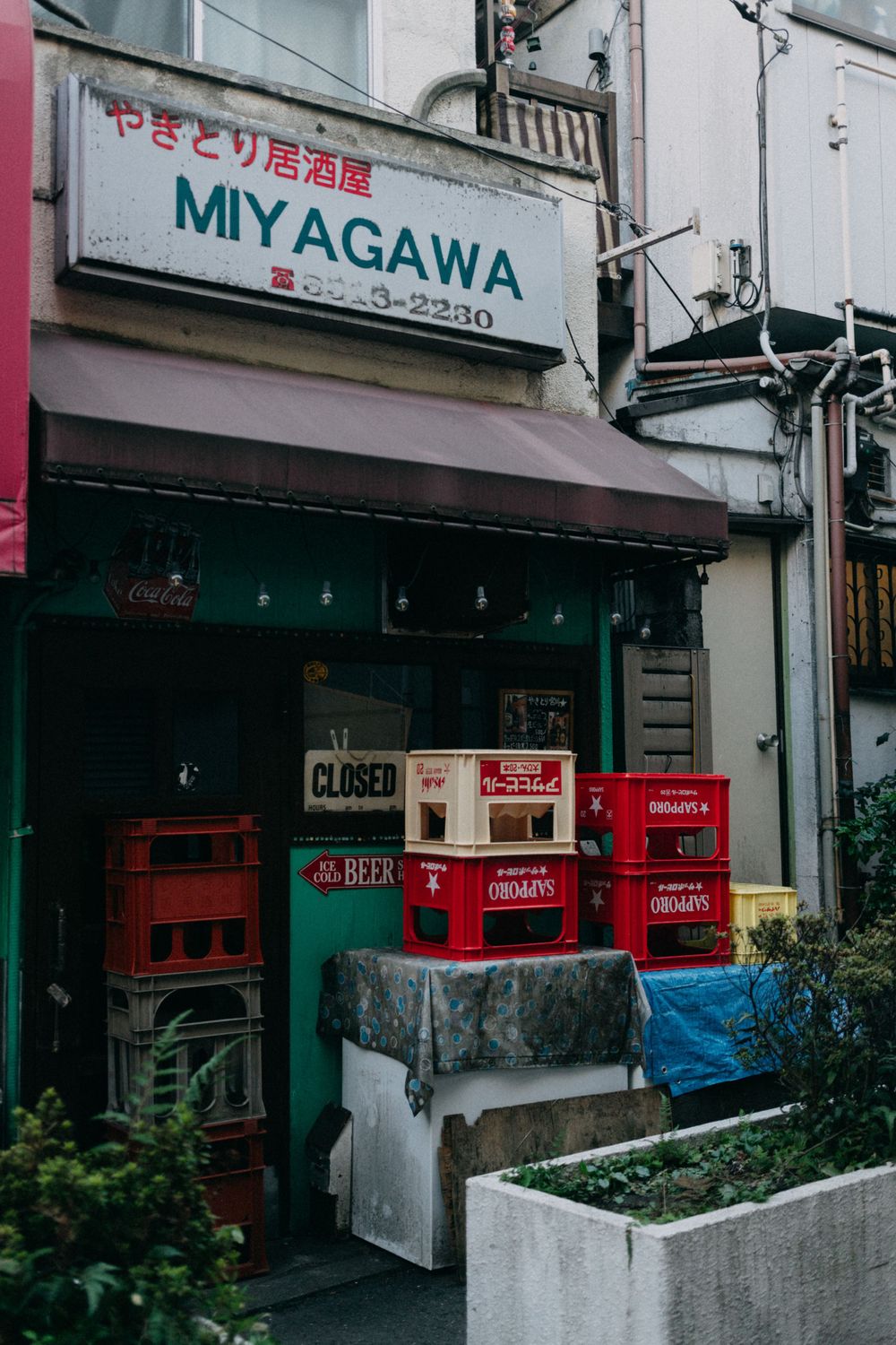 Closed Miyagawa restaurant storefront with stacked red crates.