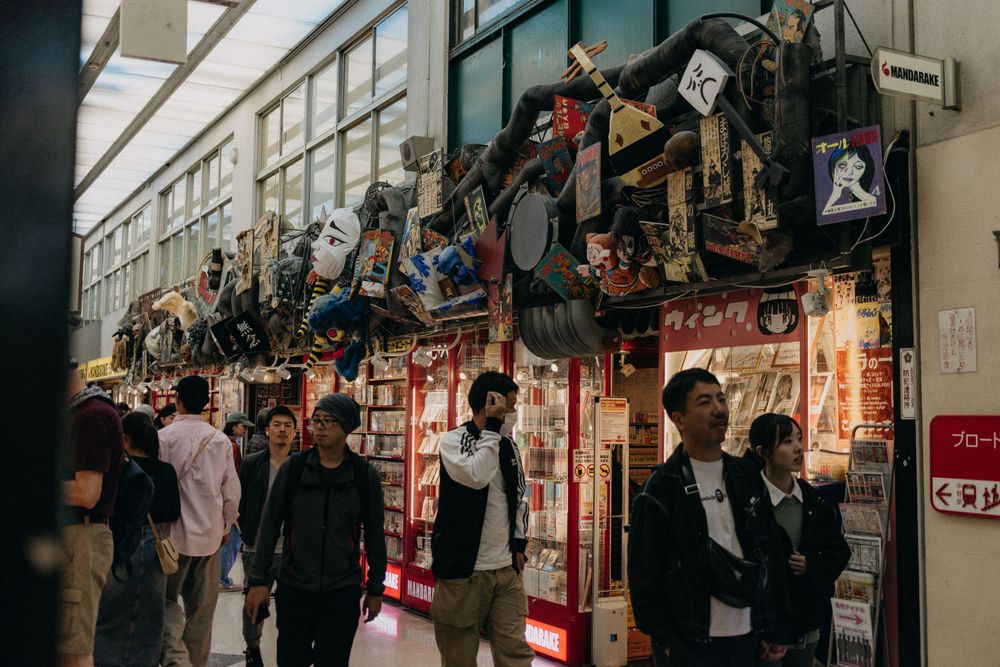 Crowded shopping arcade in Japan with hanging merchandise and store displays.
