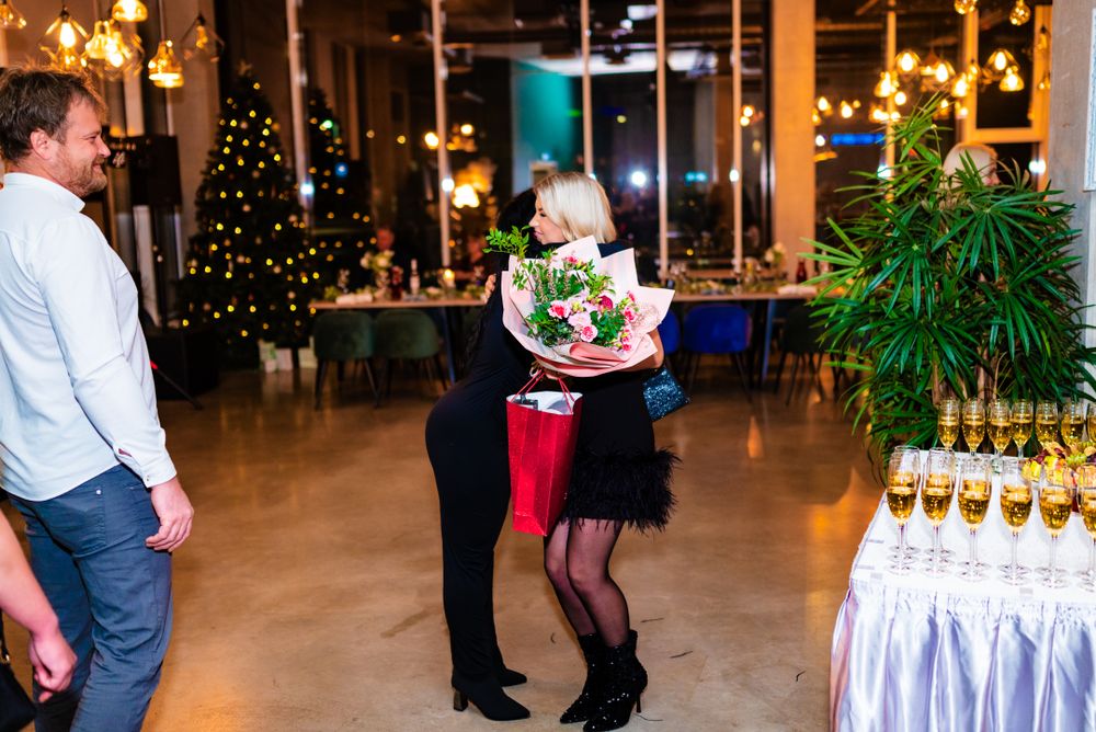 Couple embracing at an elegant holiday party with champagne display and Christmas decorations.