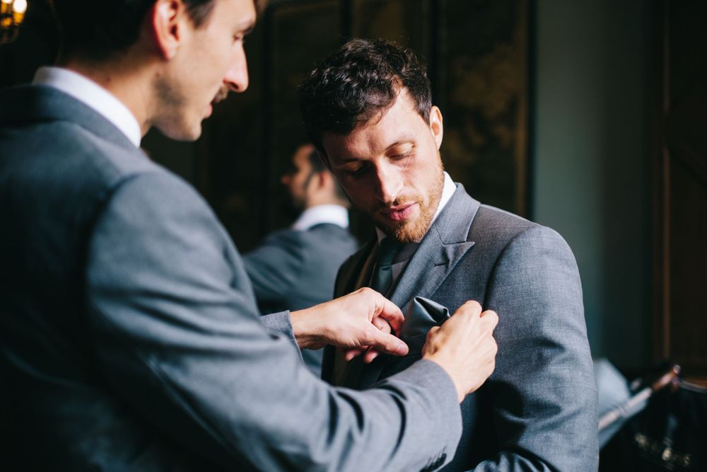 Groomsmen helping with formal attire adjustments before the ceremony.