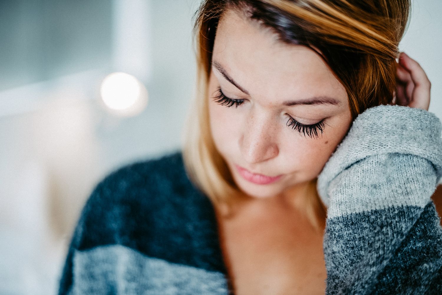Portraitaufnahme einer Frau mit geschlossenen Augen hält ihr Haar in der Hand.