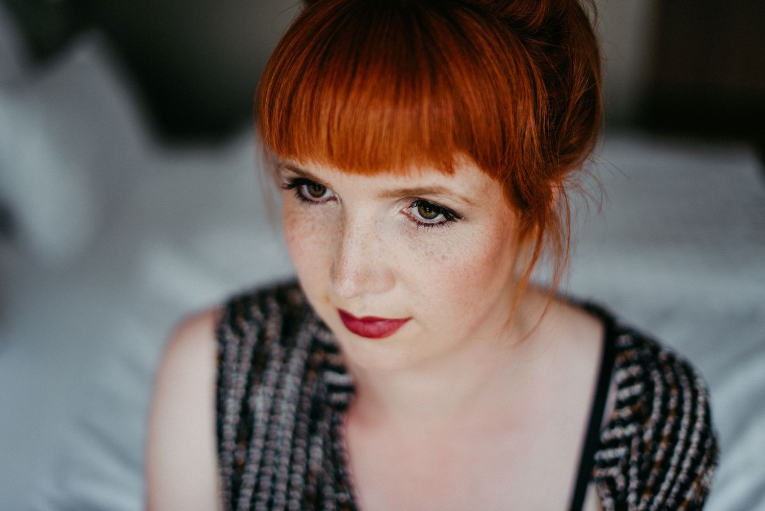 Portrait einer jungen Frau mit leuchtenden roten Haaren und rotem Lippenstift.