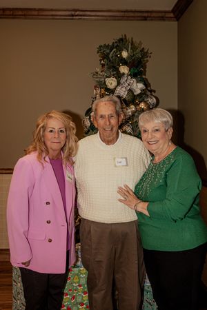 Group of people in casual attire posing together at an indoor event with a pink and green color theme.