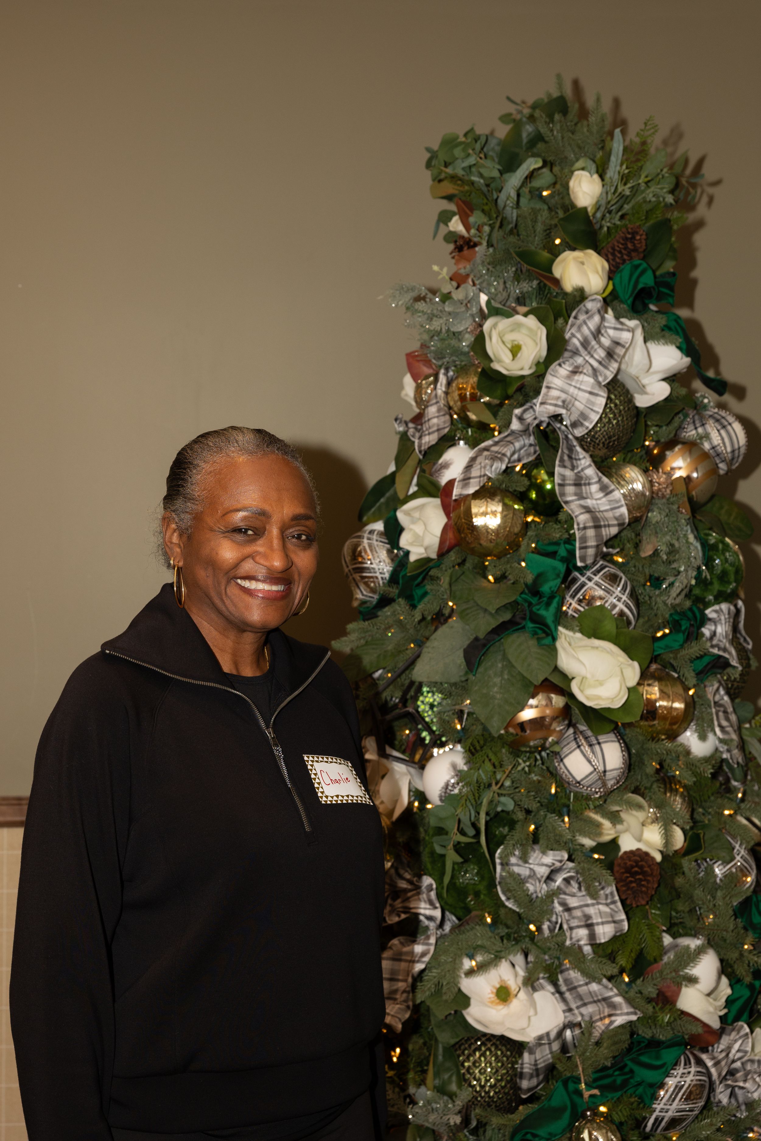 A festive holiday scene showing a decorated Christmas tree with white roses, silver ribbons and ornaments.