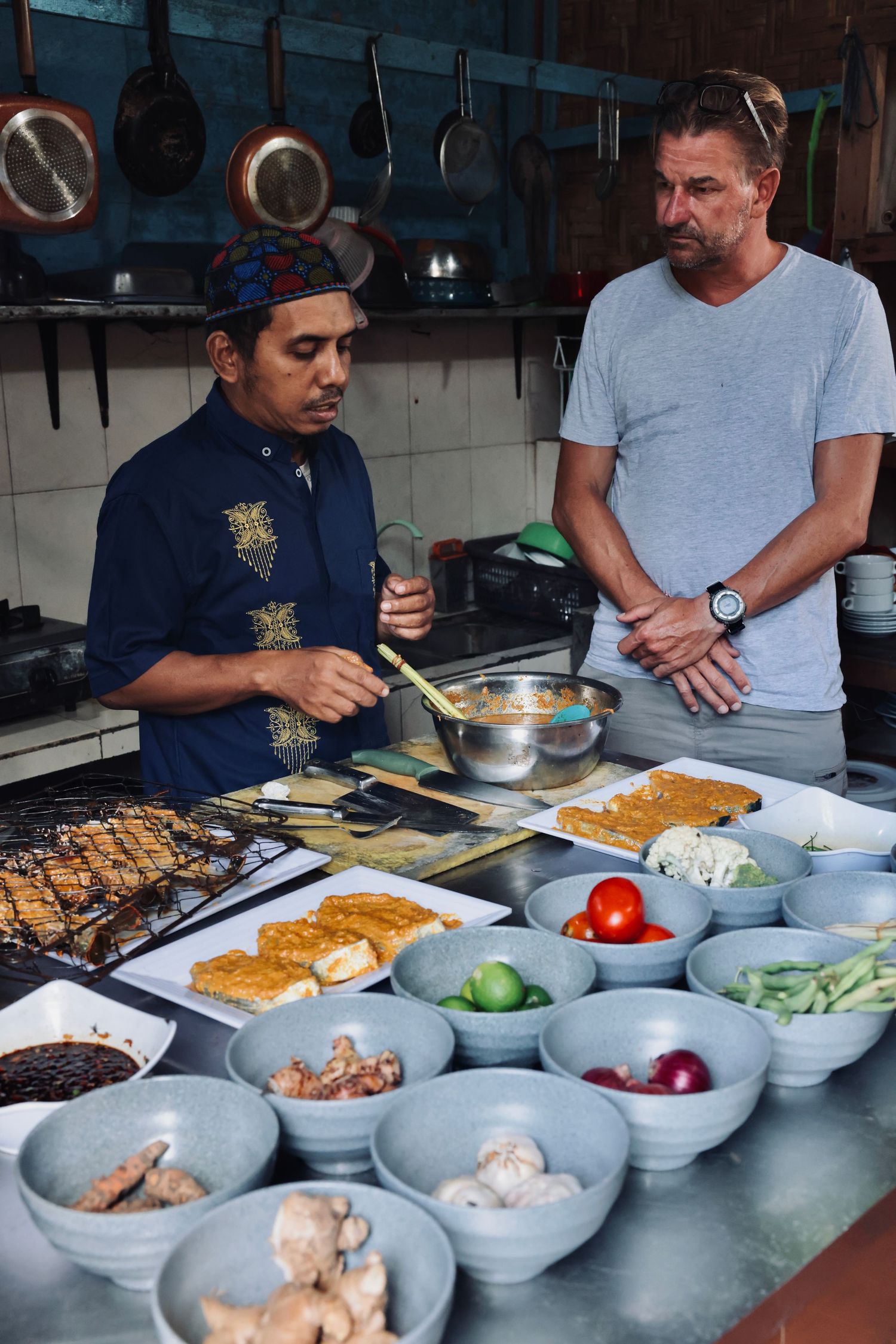 Chef preparing ingredients in commercial kitchen with various bowls of fresh produce.