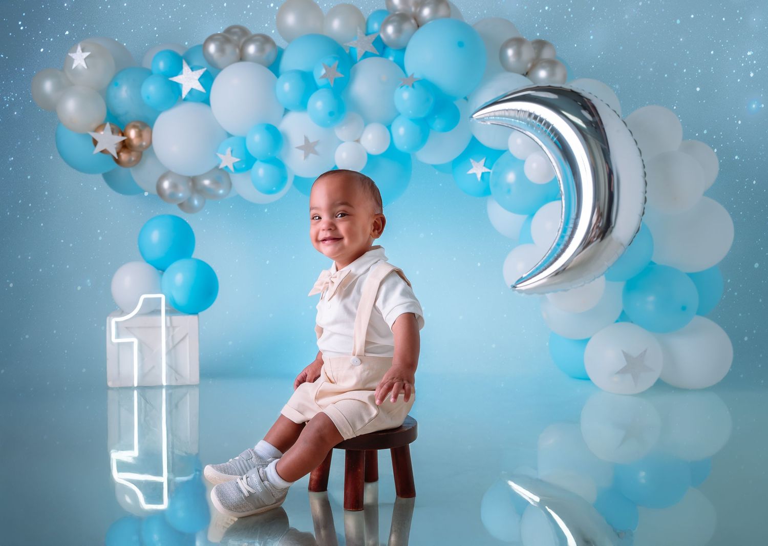 Pink Smash Cake with happy baby in blue dress, pink balloon backdrop, and first birthday cake at ILU Studio Orlando.