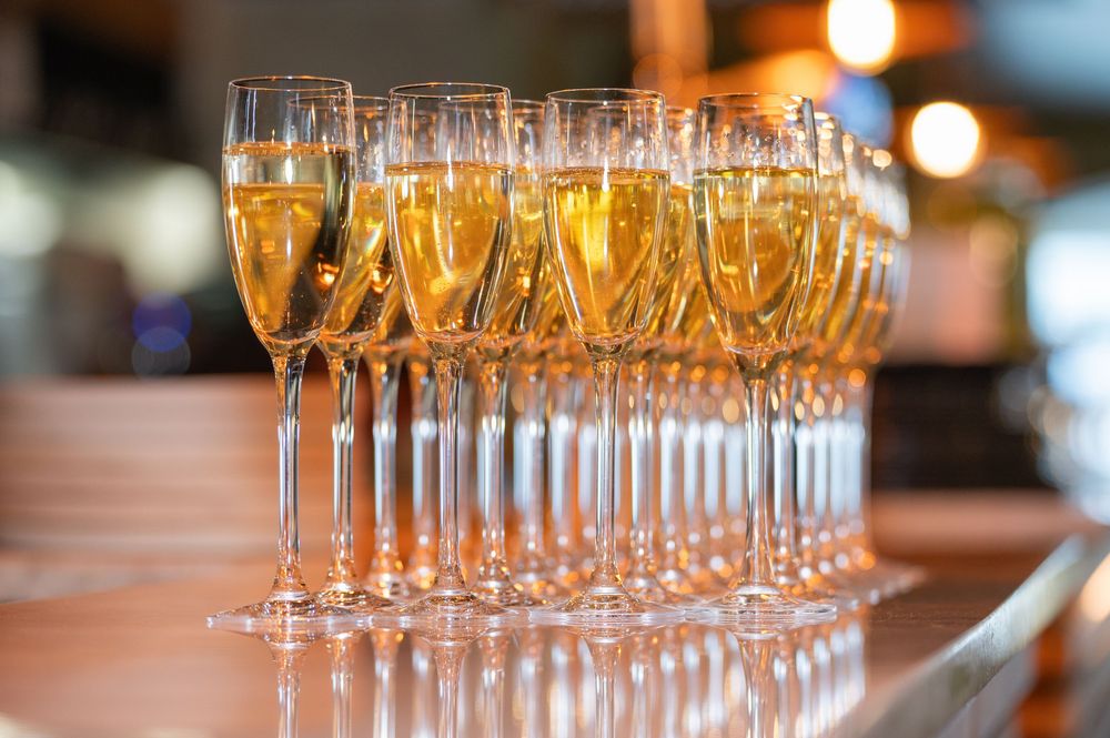 Champagne flutes lined up on a wooden surface with warm ambient lighting.