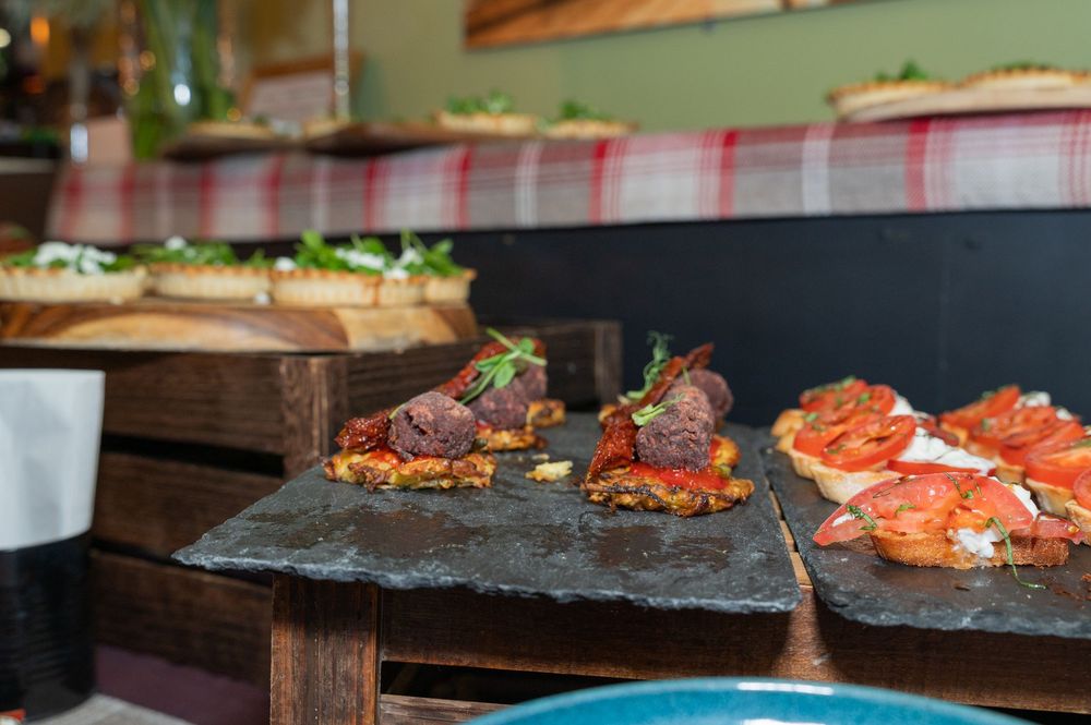 Various gourmet appetizers and canapes displayed on rustic wooden boards at a catering event.