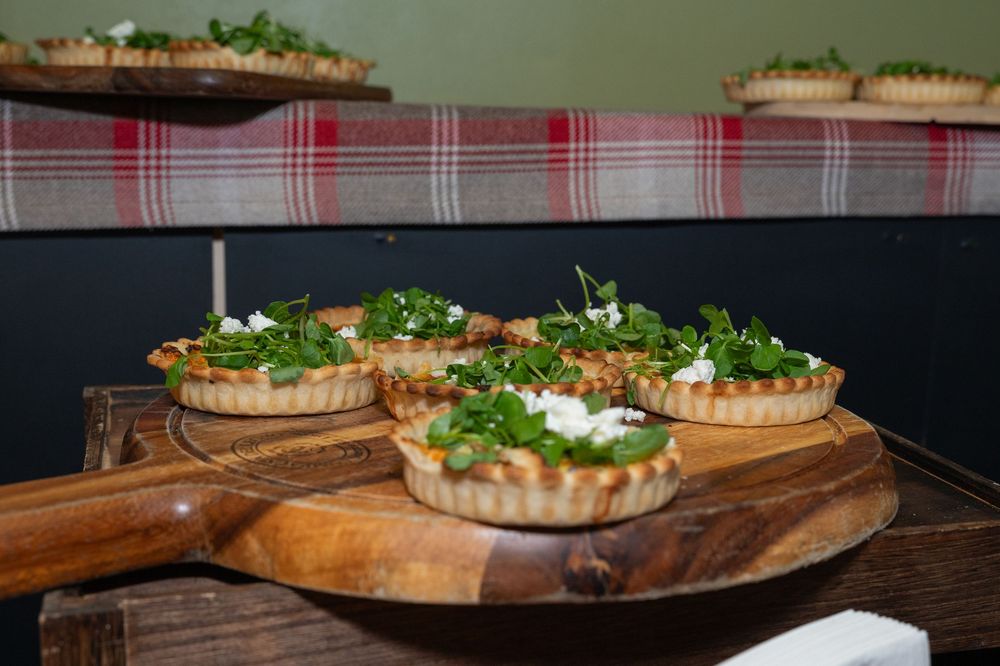 Savory tarts and appetizers arranged on wooden serving boards with fresh herbs.