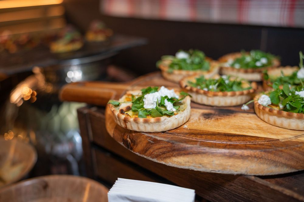 Gourmet appetizers and small bites arranged on wooden boards at an upscale event.