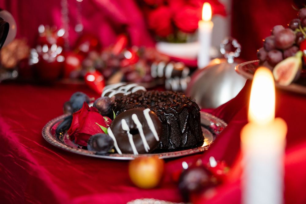 Chocolate cake with drizzle garnished with rose and fruits on a silver plate with candle.