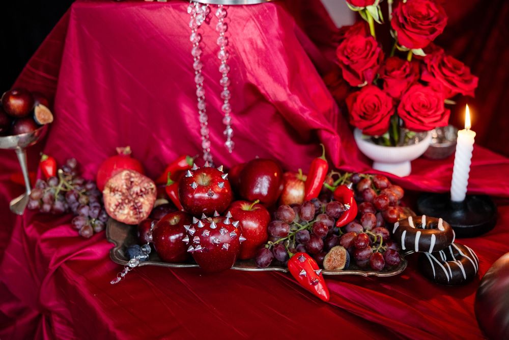 Festive red table display with pomegranates, grapes, peppers, roses, and candles.