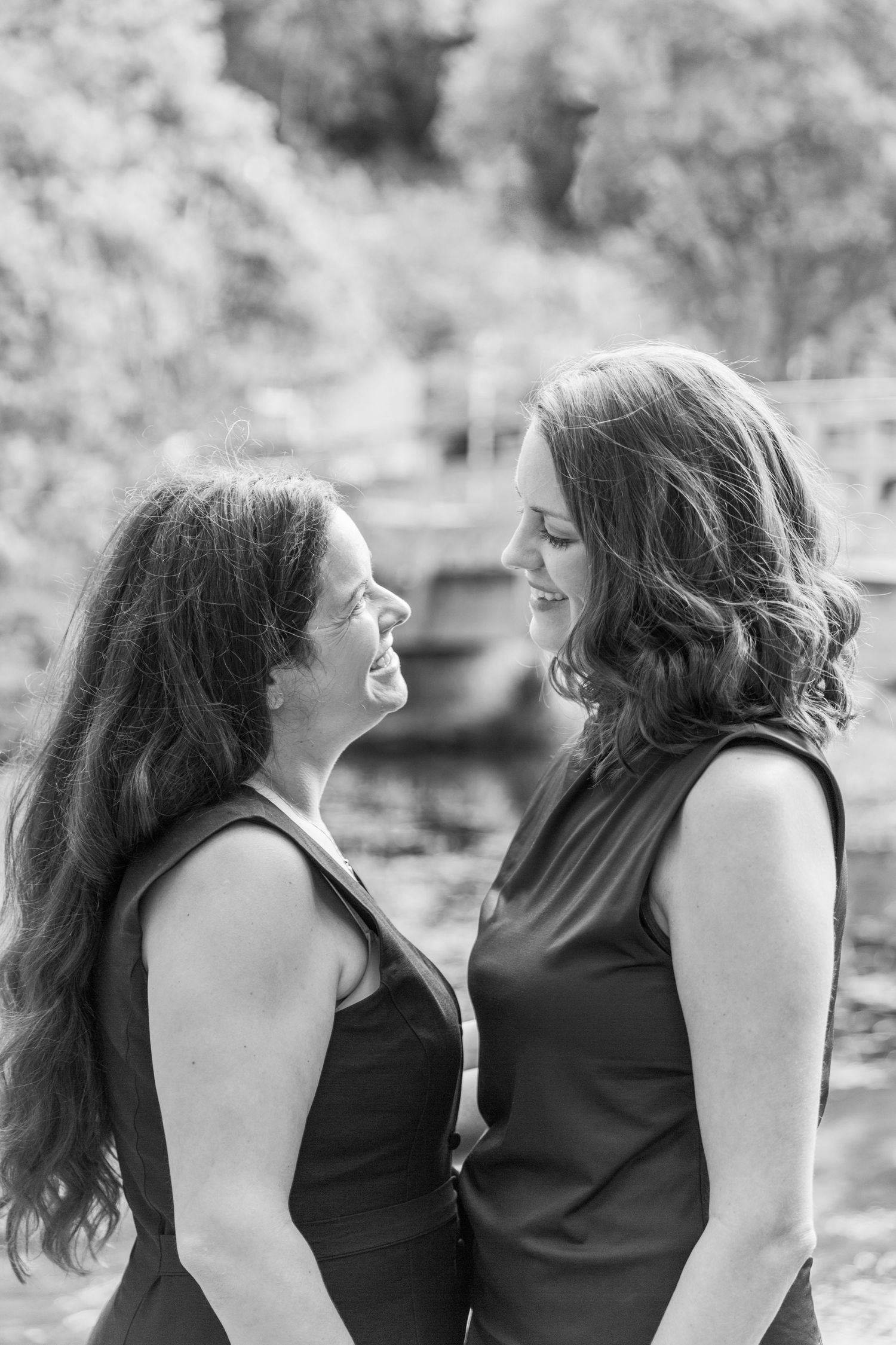 Black and white photo of newly engaged female couple sharing a loving, romantic glance with each other in Bibury The Cotswolds