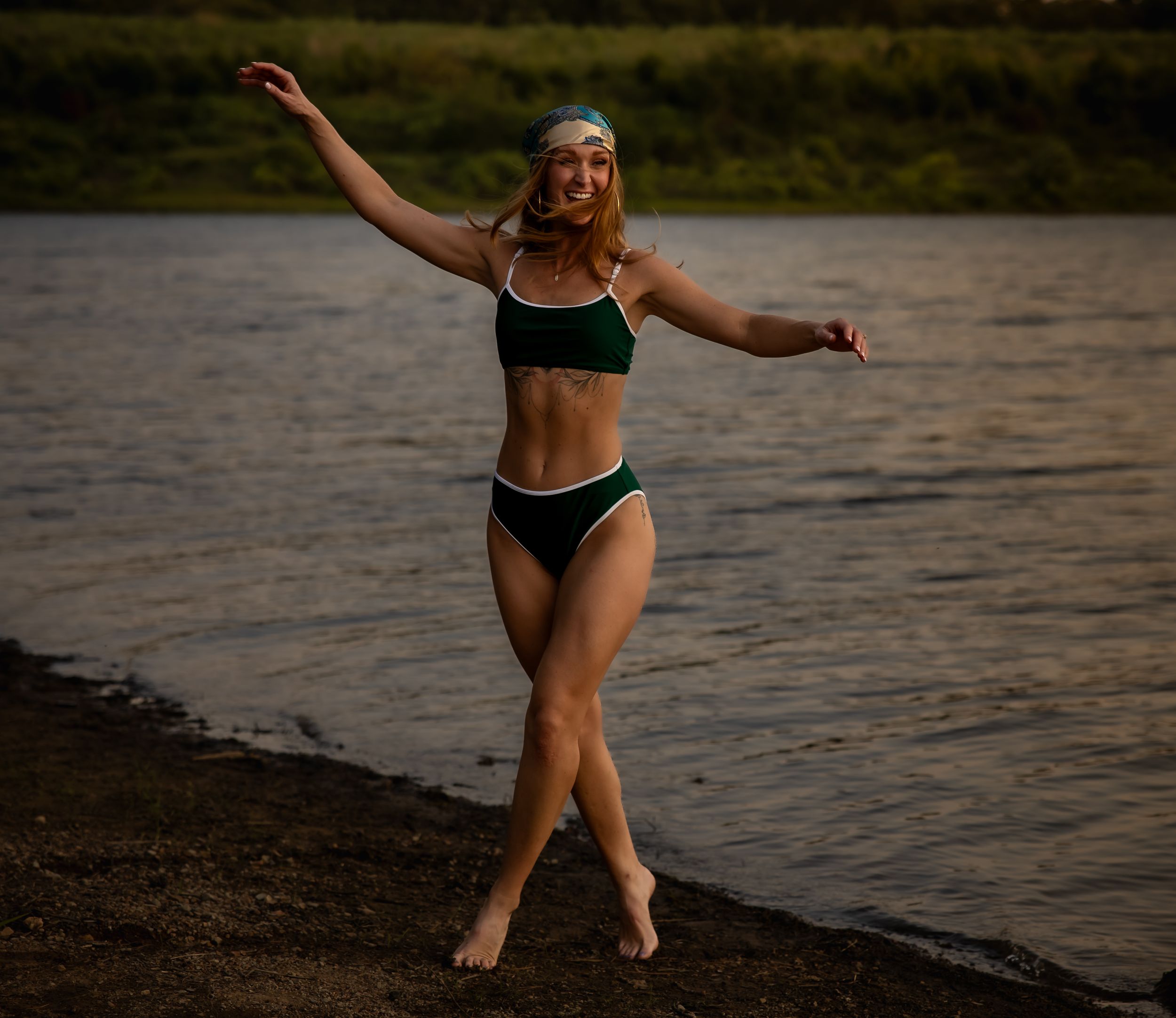 Woman enjoying playful moments in shallow water at sunset.