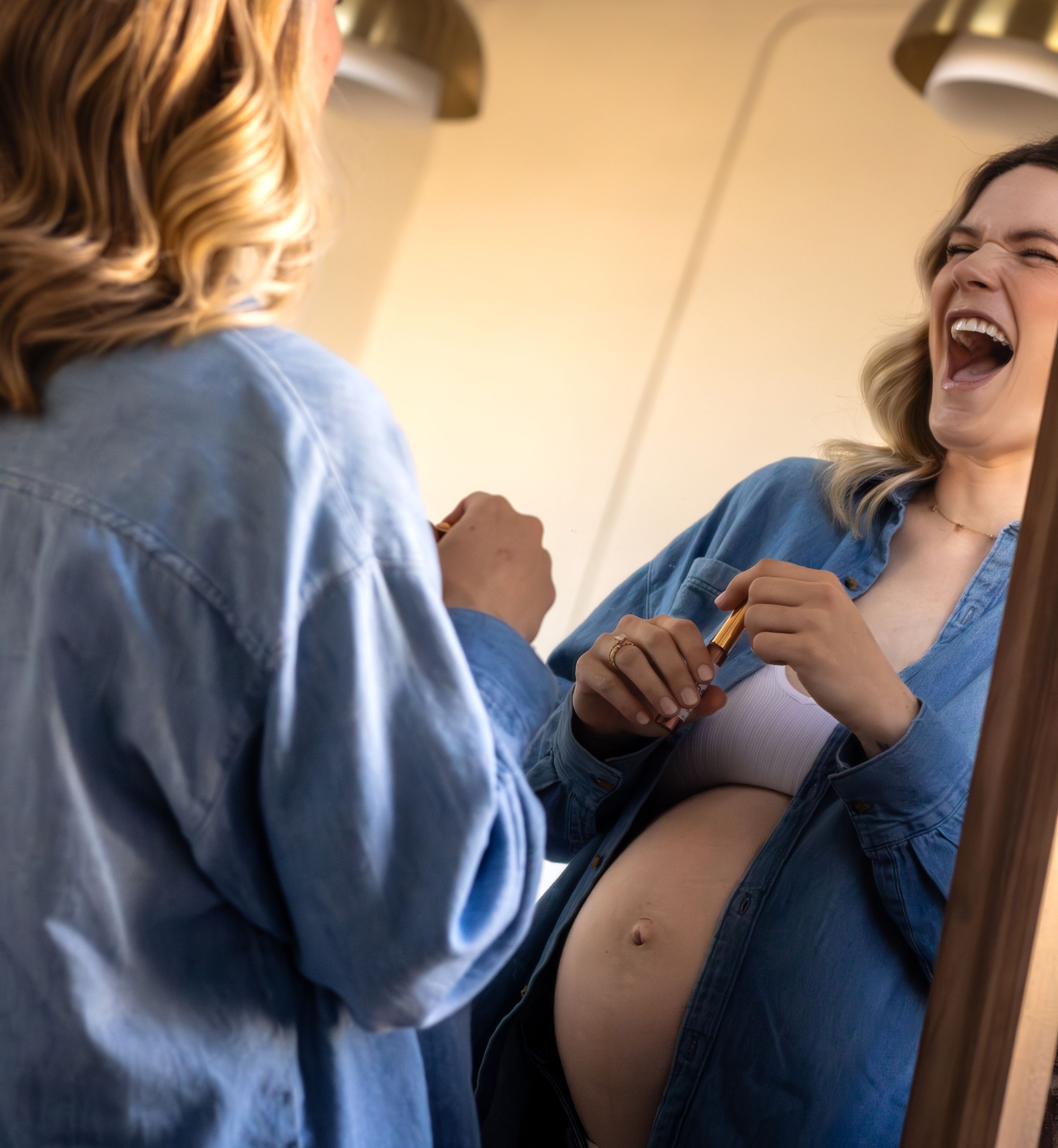 Two people laugh together while sharing a joyful moment in casual blue attire.