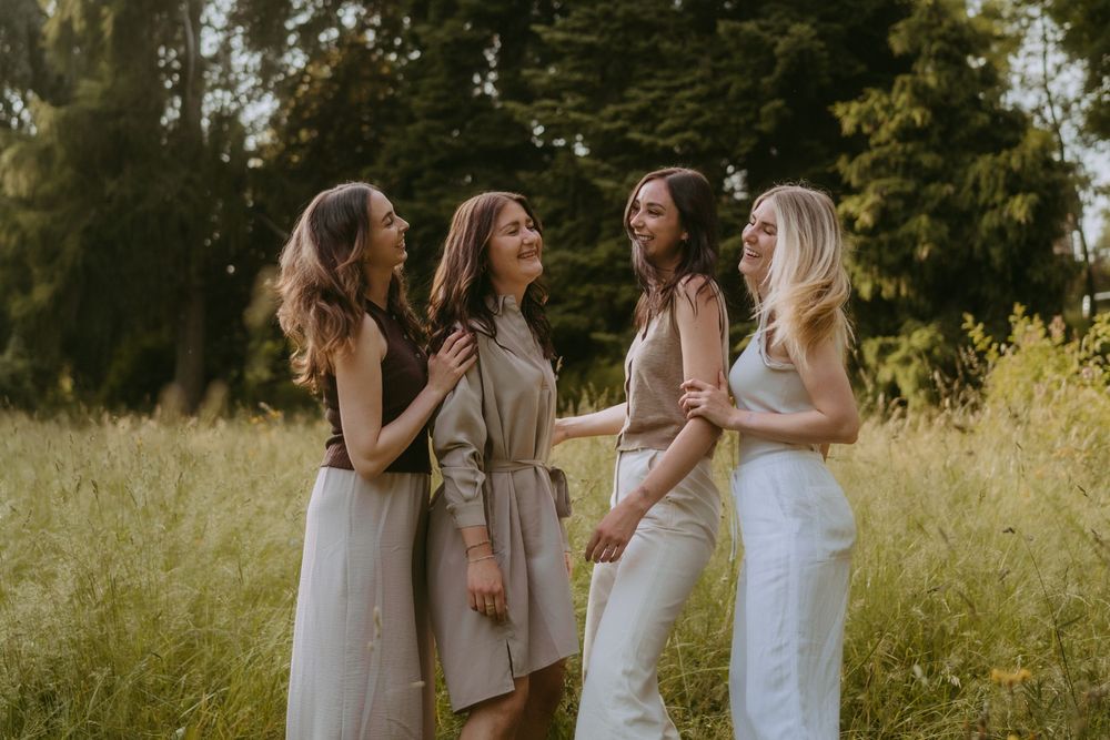 Friends in coordinated neutral outfits sharing joyful moments outdoors.
