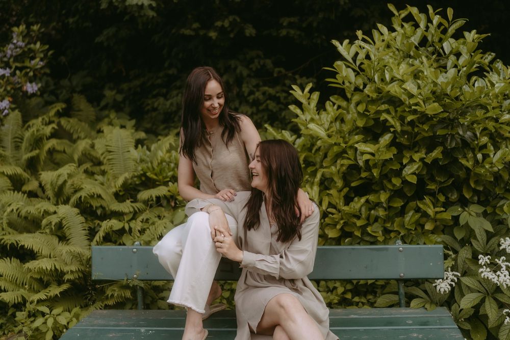 Friends relaxing on a blue park bench surrounded by lush greenery.