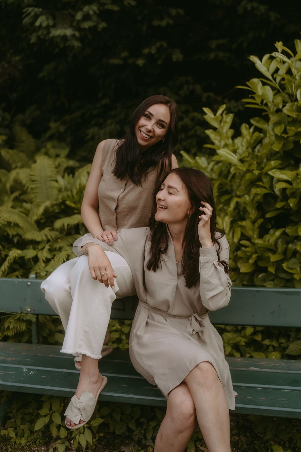 Candid moments of friendship captured on a park bench surrounded by foliage.